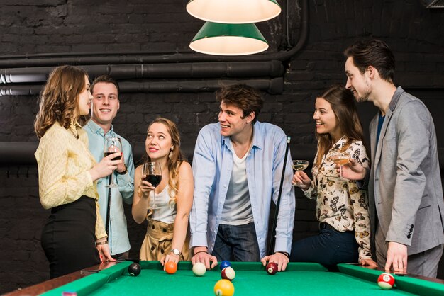 Smiling couples in club enjoying snooker and drinks