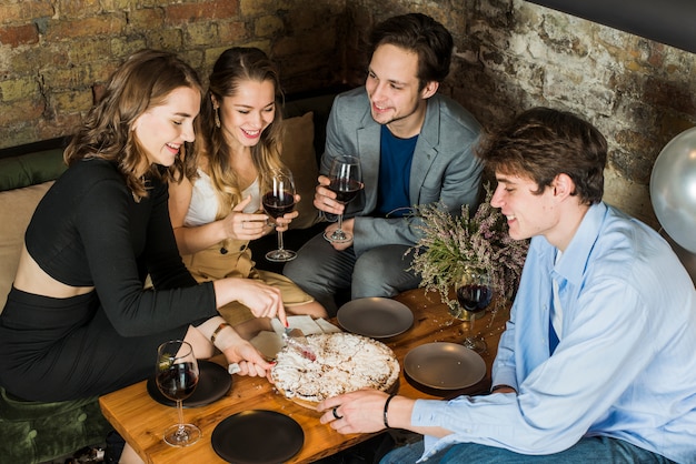 Free photo smiling couples enjoying party with pizza and wine