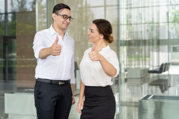 Smiling coworkers looking at each other and expressing approval