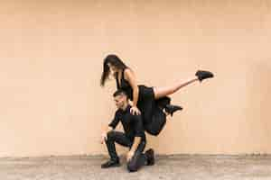 Free photo smiling dancing woman jumping over the man's shoulder