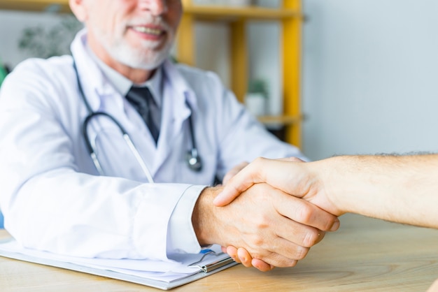 Smiling doctor shaking hand of patient