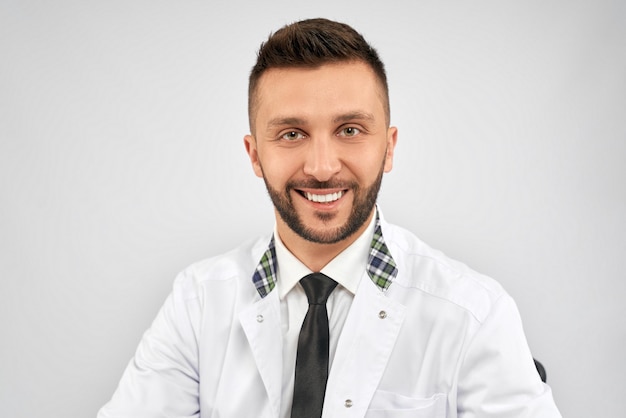 Smiling doctor sitting isolated on grey