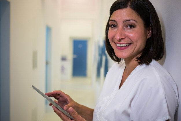 Smiling doctor using digital tablet at clinic