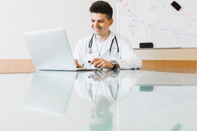 Smiling doctor working with laptop