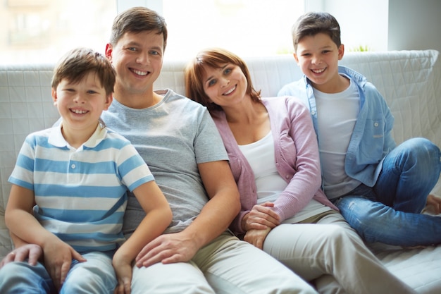 Free photo smiling family sitting on white sofa