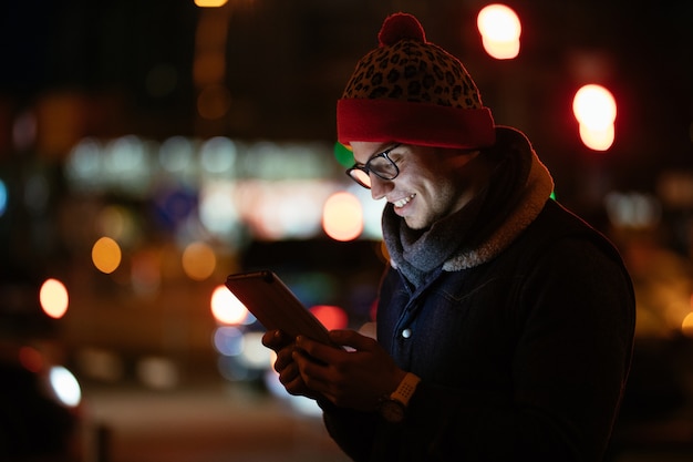 Smiling fashionable man in eyeglasses using his mobile phone 