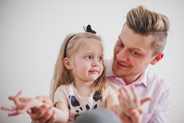 Smiling father playing with his daughter's hands