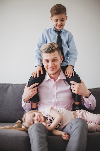 Free photo smiling father with son on his shoulders and daughter on his knees