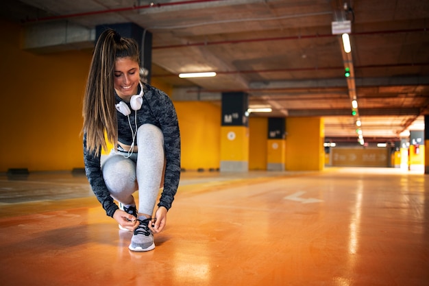 Free Photo smiling female athlete tying her shoelace and preparing for training