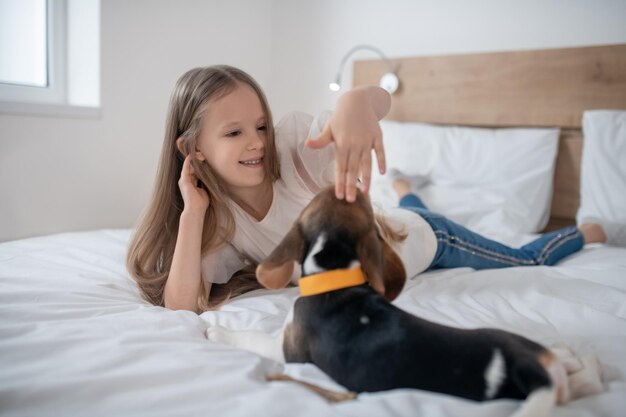 Smiling female child patting the beagle on the head