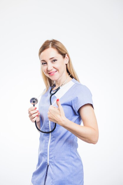 Smiling female dentist gesturing thumbs up on white background