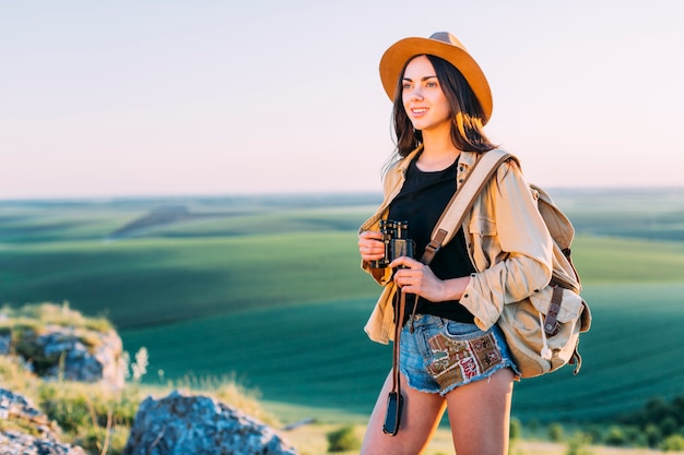 Smiling female hiker holding binocular