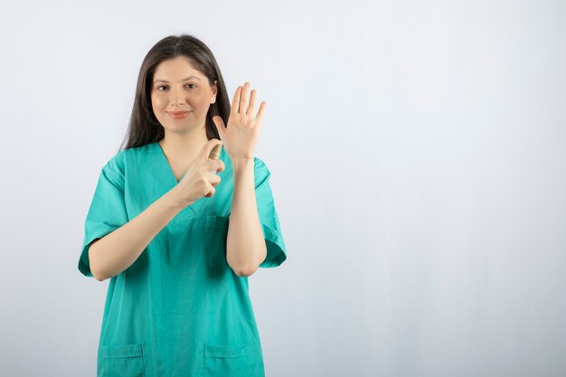 Smiling female nurse spraying her hand on white. 