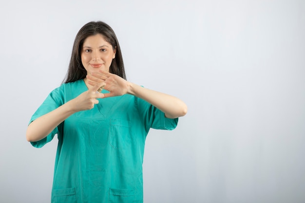 Smiling female nurse spraying her hand on white. 