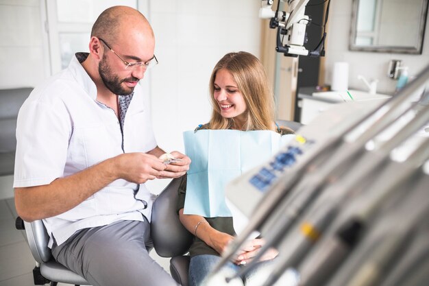 Smiling female patient looking at dentist working on dental jaw