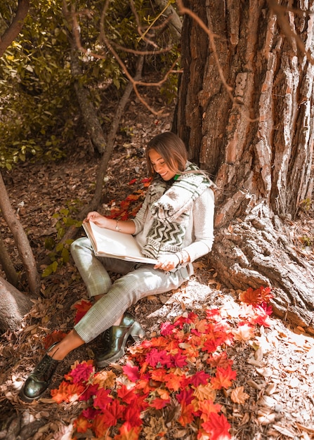 Free Photo smiling female reading in autumn forest