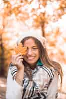 Free photo smiling female with autumn leaf