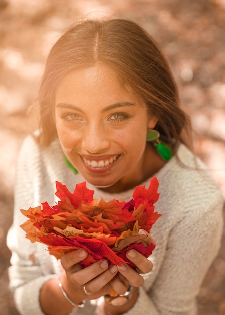 Free photo smiling female with autumn leaves