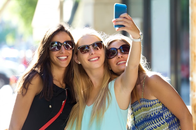 Smiling females making selfie on street