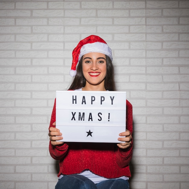 Free photo smiling festive woman holding christmas sign