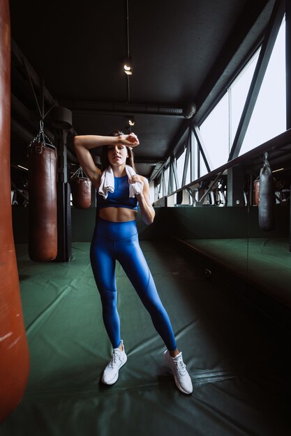 Smiling fit girl holding towel and taking rest in gym.