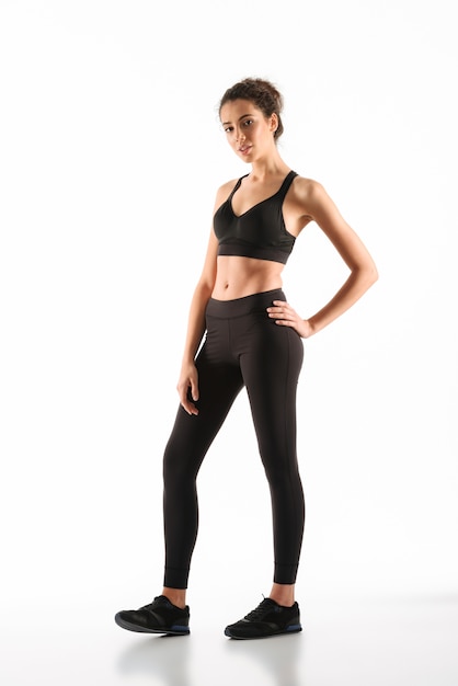 Smiling fitness woman holding arm on hip 