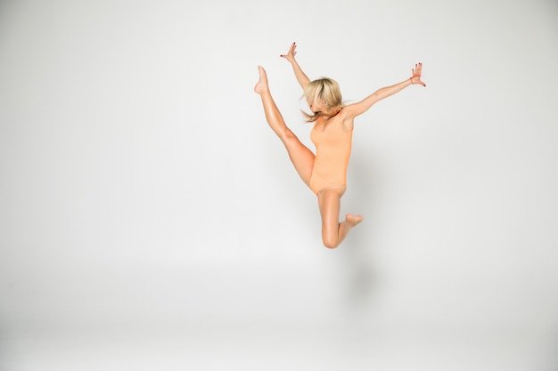 Smiling flexible girl gymnast in a costume doing stretching exercise