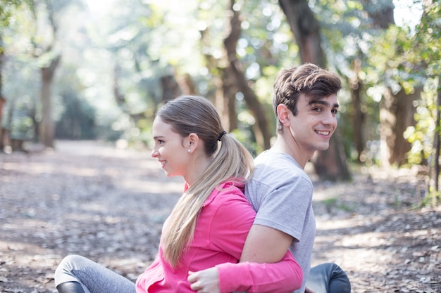 Smiling friends stretching together sitting in the park