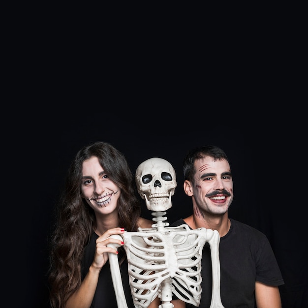 Free Photo smiling friends with creepy skeleton