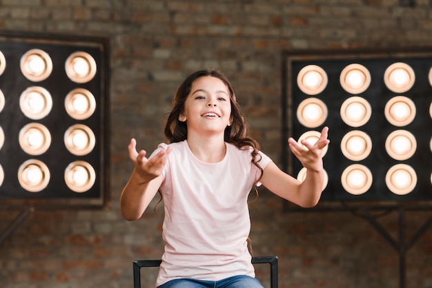 Free photo smiling girl acting in studio with stage light in the background