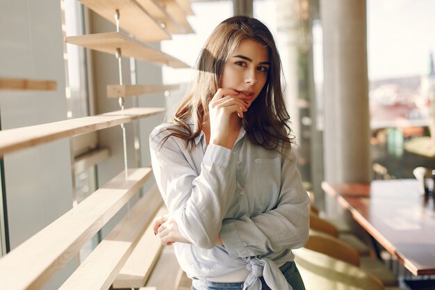 Smiling girl in a blue shirt standing near window