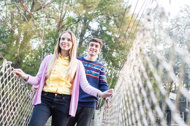 Smiling girl crossing the bridge with her friend