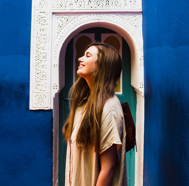 Free Photo smiling girl in front of arched door side view