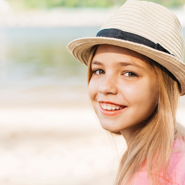 Smiling girl in hat at shore