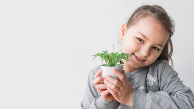 Free photo smiling girl holding plant