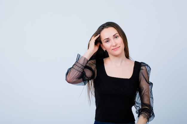 Smiling girl is looking at camera by holding hand on head on white background