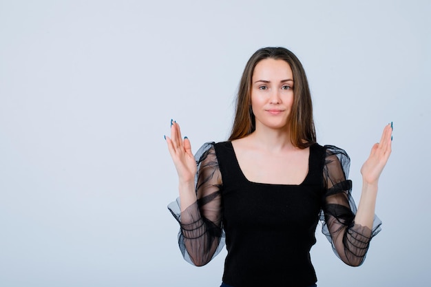 Smiling girl is looking at camera by holding hands up on white background