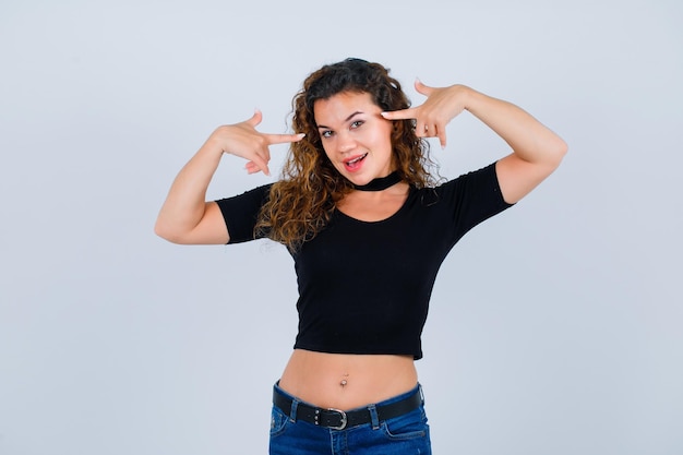 Smiling girl is pointing her head with forefingers on white background