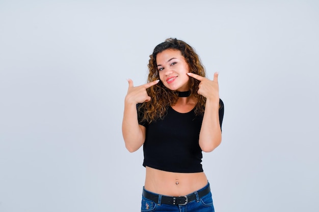 Smiling girl is pointing her smile with forefingers on white background