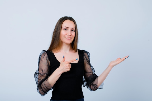 Smiling girl is showing perfect gesture and pointing right with hand on white background