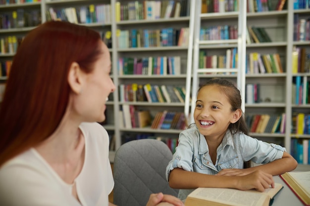 Smiling girl looking at woman sitting at table