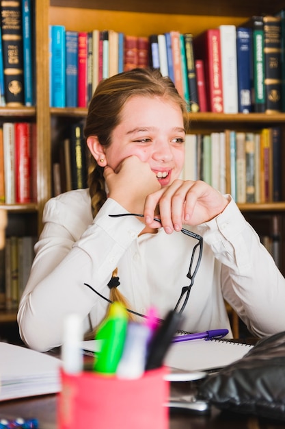 Free Photo smiling girl sitting with notebook in library 