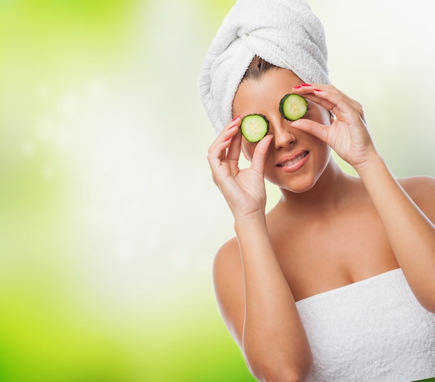 Free photo smiling girl with towel on head and cucumbers on eyes