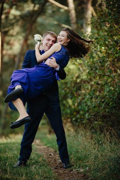 Smiling groomsman carrying laughing bridesmaid