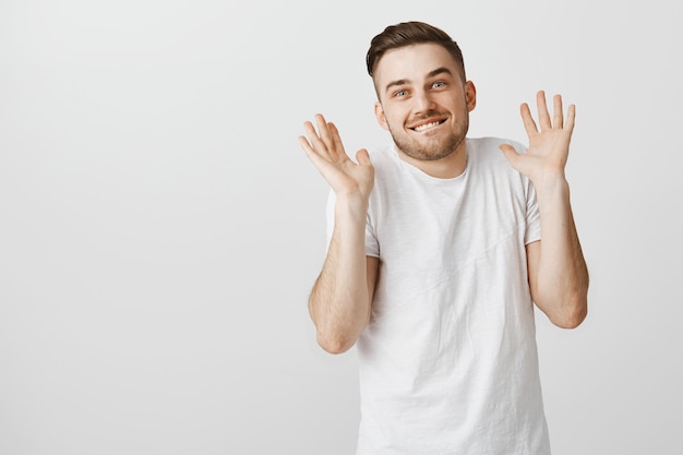 Smiling guy lying he don't know anything, raising hands up with cunning grin