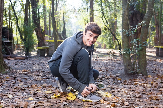 Free Photo smiling guy tying laces of trainers before training