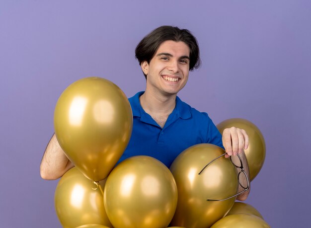 Smiling handsome caucasian man stands with helium balloons holding optical glasses 