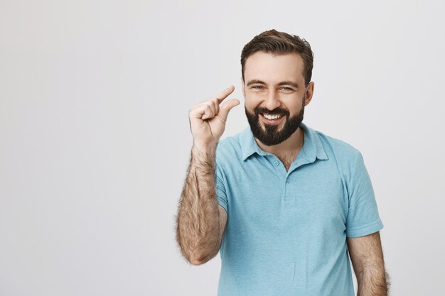 Smiling handsome man showing something tiny or small