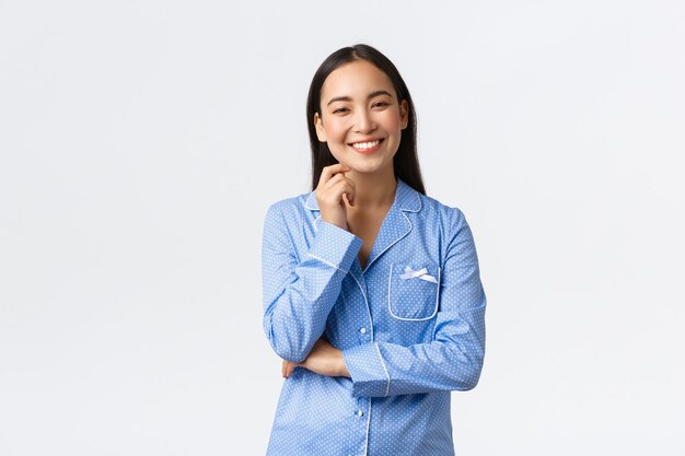 Smiling happy asian girl standing in pajamas and looking at camera upbeat. Female student arrange sleepover fun night with girlfriends, having fun. Girl having fun on slumber party