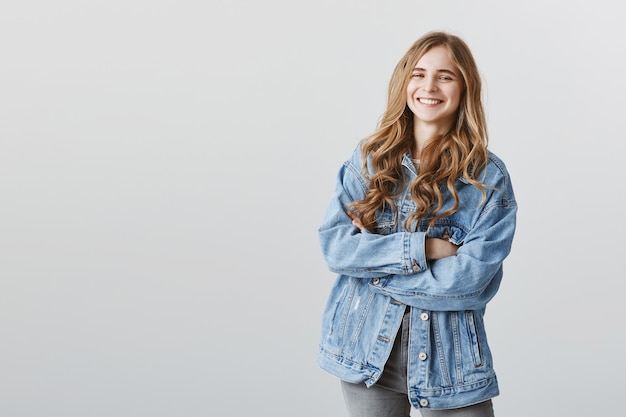 Free photo smiling happy pleased girl in denim jacket with arms crossed